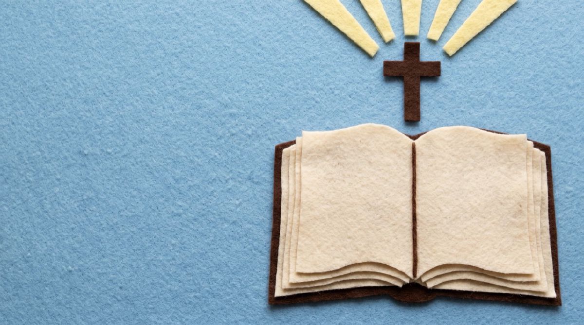 Felt open Bible beneath a wooden cross